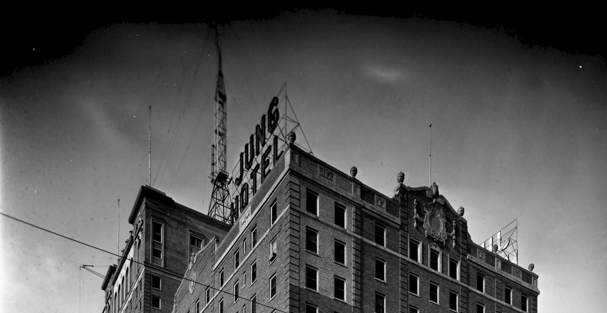 The image shows the upper portion of a building with a sign reading "JUNG HOTEL," with a tower structure visible on the roof.