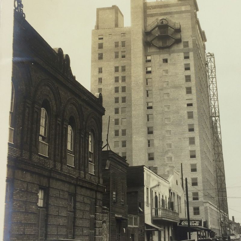 A street scene with vintage cars, historic brick buildings, and a tall, clocked skyscraper are visible in the image.